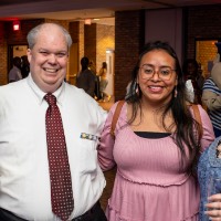 Group of people take a photo with each other and the girls on the end hold up their champagne flutes.